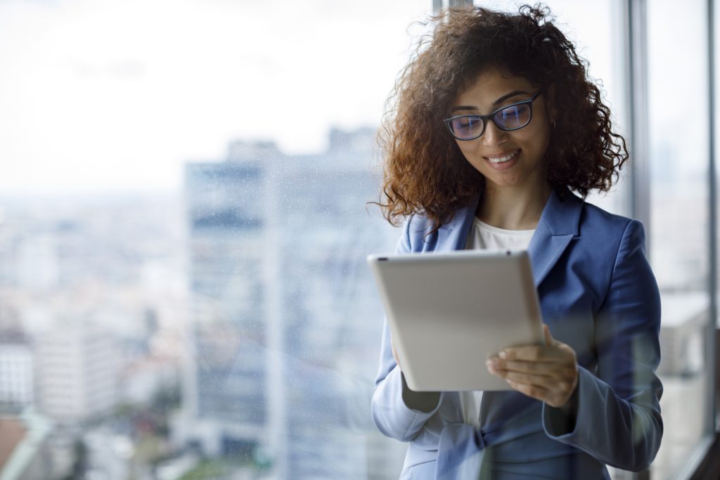 Young smiling businesswoman using using digital tablet in office